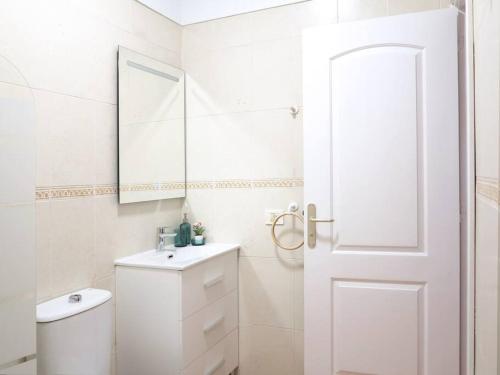 La salle de bains blanche est pourvue de toilettes et d'un miroir. dans l'établissement Las Palmeras, à Puertito de Güímar