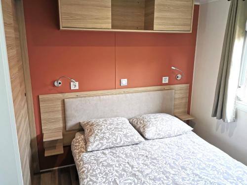 une chambre avec un lit avec un mur orange dans l'établissement La Passionnatta Piscines chauffees, à Saint-Hilaire-de-Talmont