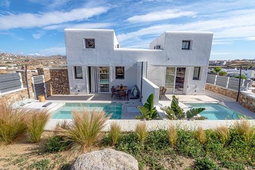 a white house with a swimming pool in front of it at Le Palme Mykonos in Klouvas
