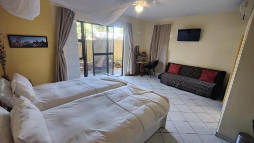 a hotel room with two beds and a couch at Maison Ambre Guesthouse in Windhoek