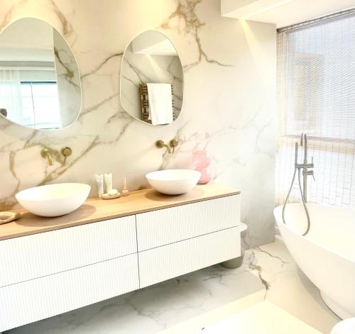 une salle de bain avec deux lavabos, une baignoire et un miroir dans l'établissement Moscowa# Ibiza, à Cannes