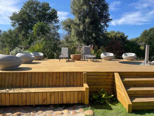 a wooden deck with three chairs and a bench at Guinevere Guest Farm in Tulbagh