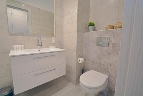 a white bathroom with a toilet and a sink at Sun Towers - Apartamenty Bryza - Apartamenty z parkingiem in Świnoujście