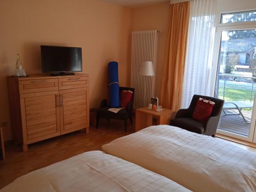 a bedroom with a bed and a television and chairs at Menschels Vitalresort in Meddersheim