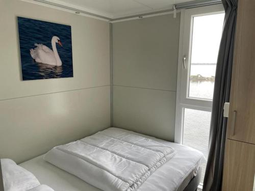 a room with a bed with a picture of a swan at Houseboot Cormorant, lake view in Biddinghuizen