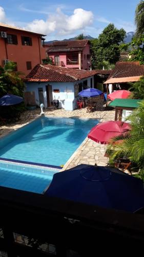 a swimming pool with umbrellas in front of a house at POUSADA BELLA SPIAGGIA in Paraty