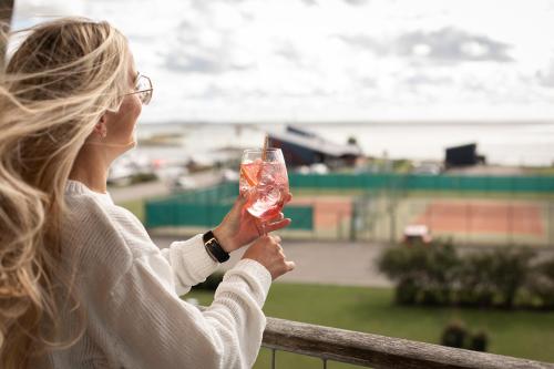 Georg Ots Spa Hotel في كوريساري: امرأة ممسكة بزجاج النبيذ أمام سفينة