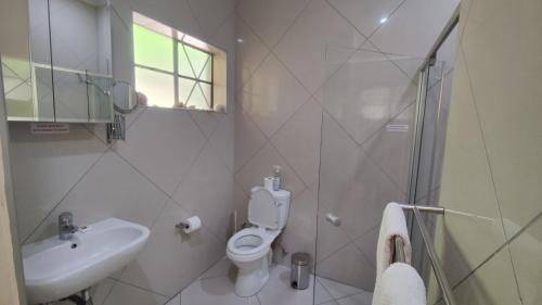a bathroom with a toilet and a sink and a shower at Maison Ambre Guesthouse in Windhoek
