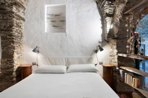 een slaapkamer met een wit bed in een stenen muur bij Green Cactus House in La Spezia