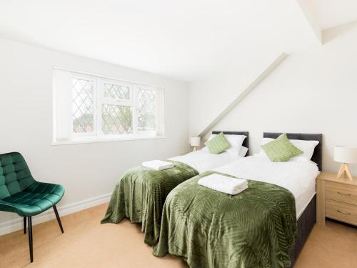 2 Betten in einem Schlafzimmer mit einem grünen Stuhl in der Unterkunft Pass the Keys Self Contained 2 Bed with Parking Leamington Spa in Leamington Spa