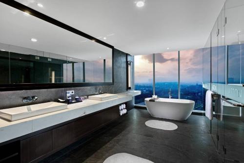 a bathroom with two sinks and a tub and a window at ASTON Sidoarjo City Hotel & Conference Center in Sidoarjo