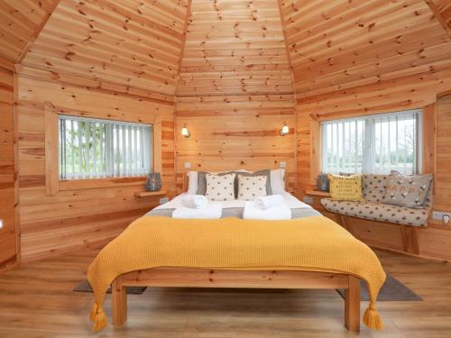 a bedroom with a bed in a wooden cabin at Honeybee Retreat in Pentney