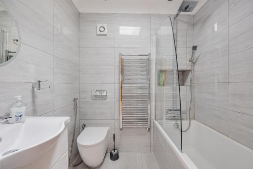 a bathroom with a toilet and a tub and a sink at Entire Large Detached Bungalow The Star of Hatfield in Hatfield