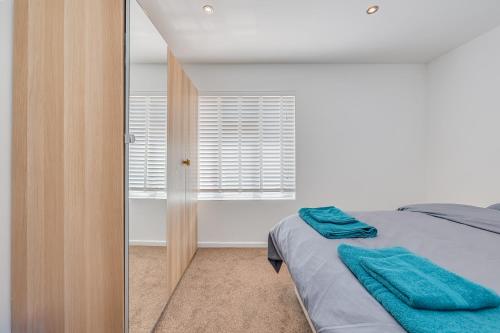 Schlafzimmer mit einem Bett und einem Spiegel in der Unterkunft Entire Large Detached Bungalow The Star of Hatfield in Hatfield