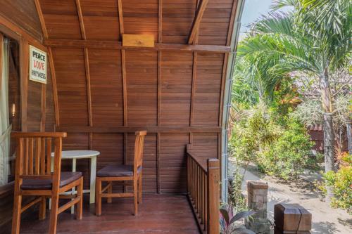 a wooden porch with two chairs and a table at Maha Nusa Menjangan in Banyuwedang