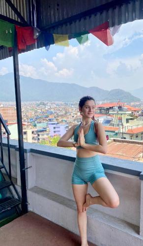 a woman standing in front of a window at Yog Hostel- Rooftop Yoga & Backpacker Social Stay in Thamel, Kathamndu in Kathmandu