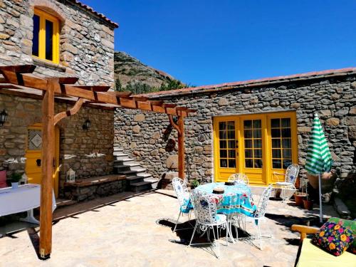 un patio con tavolo, sedie e un edificio di Ilios Guest House a Gokceada Town