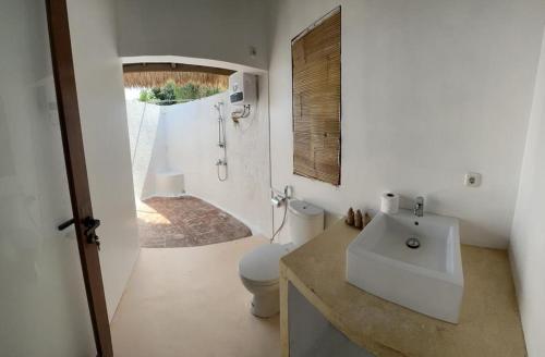 a white bathroom with a sink and a toilet at Khabita Beach Resort in Lembar