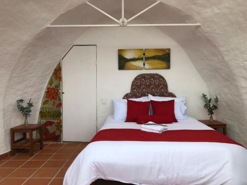 1 dormitorio con 1 cama blanca grande con almohadas rojas en Glamping Sierra de Luna en Villa de Leyva