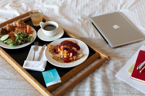 a tray with two plates of food and a laptop at Georg Ots Spa Hotel in Kuressaare