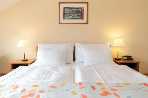 a bedroom with two beds with white sheets and two lamps at Hotel Orion in Prague