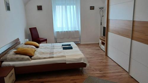 a bedroom with a bed with a chair and a window at Milla Apartmanok in Eger