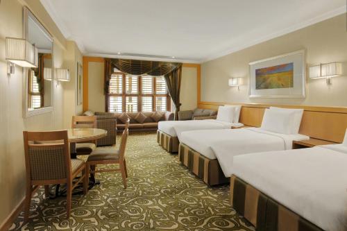 a hotel room with four beds and a table at Makkah Towers in Makkah