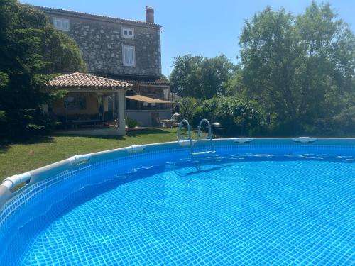 a large blue swimming pool in front of a house at Stone house Chiara Seaview in Funtana