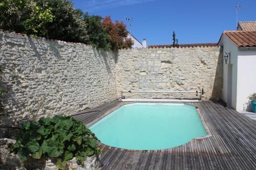 een zwembad voor een stenen muur bij Les Arums - Maison de Vacances in Saint-Xandre
