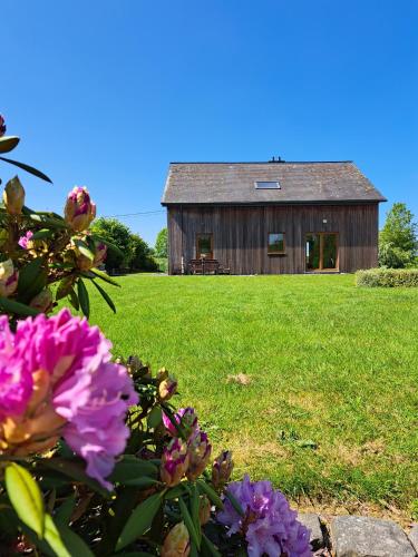an old barn in the middle of a field with flowers at Gite A bicyclette in Dinez