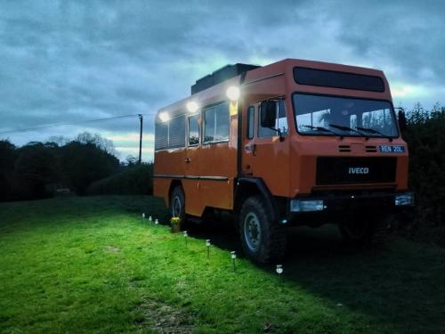 an orange bus parked in a grass field at Glamp in Style in a Converted Army Truck in Battle