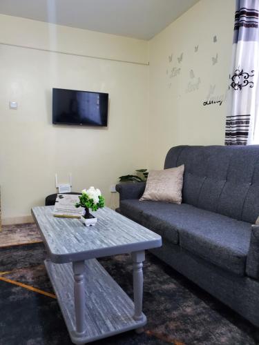 ein Wohnzimmer mit Sofa und Tisch in der Unterkunft 2 BR, TreasureTree Homes, Thika. in Thika
