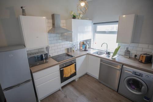 a kitchen with white cabinets and a washer and dryer at The Royalty in Sunderland