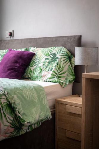 a bed with green and purple pillows on it at The Royalty in Sunderland