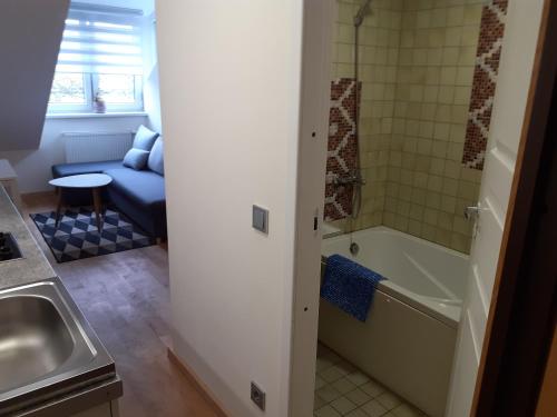 a bathroom with a tub and a sink and a couch at Loft style apartments in Kaunas center in Kaunas