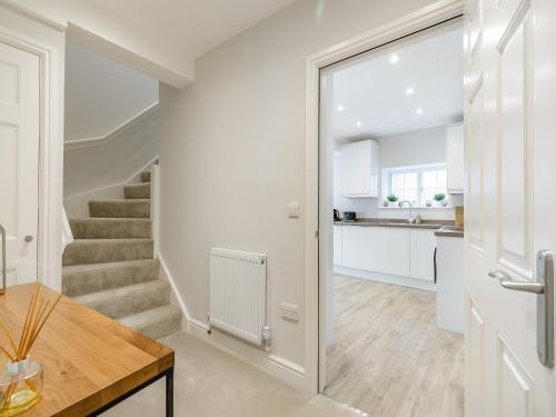 a white kitchen with stairs and a table at Gate House Apartment in Westerham