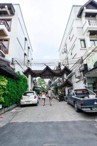 a couple of people walking down a street with cars at Chiang Mai Walking Street Home old town in Chiang Mai