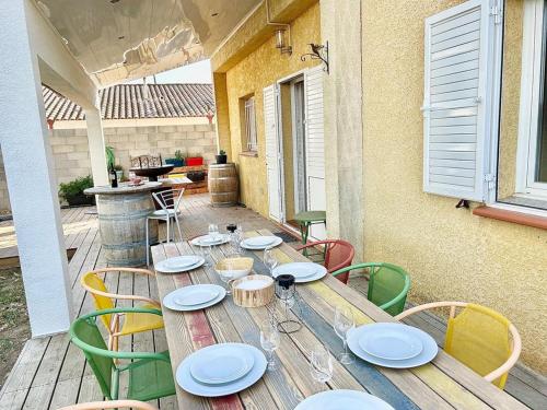 una mesa de madera con platos y sillas en el patio en Villa au calme avec Piscine Jacuzzi, en Ventenac en Minervois