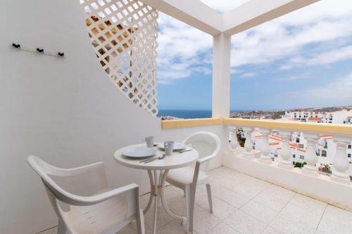 un balcone bianco con tavolo, sedie e vista sull'oceano di Terrace View Studio ad Adeje