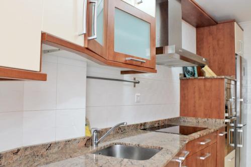 a kitchen with wooden cabinets and a sink at Abad Paterno - 3008 in Santoña