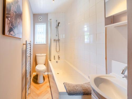 a bathroom with a toilet and a tub and a sink at Kew Cottage in Brotton