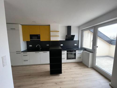 eine Küche mit weißen Schränken und einer schwarzen Arbeitsplatte in der Unterkunft Joanna Apartment - Schwetzingen 3 in Schwetzingen