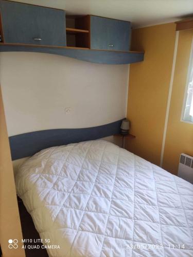 1 dormitorio con 1 cama blanca y armarios azules en Camping les tilleuls du caminel Mobile home 97, en Sarlat-la-Canéda