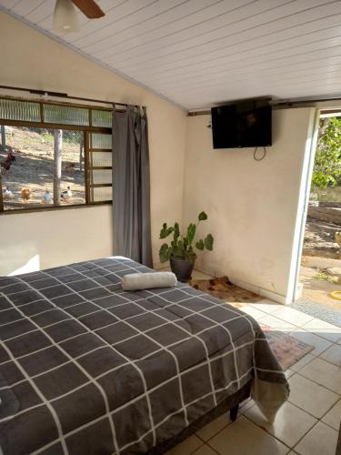 a bedroom with a bed and a flat screen tv at Pousada Recanto Alegre in Campestre