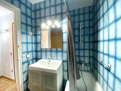 La salle de bains est pourvue de carrelage bleu, d'un lavabo et d'une douche. dans l'établissement Estel, à L'Escala