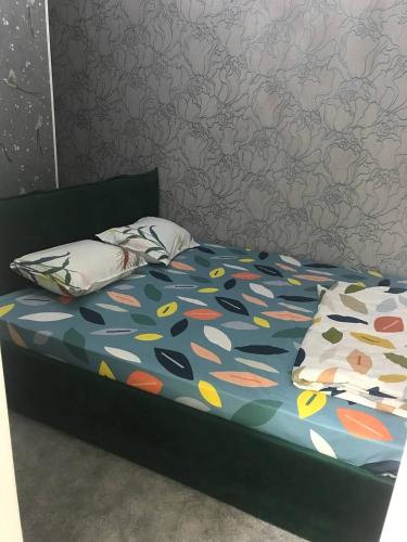 a bed with a colorful comforter and two pillows at GREEN HAUS ONE in Tashkent