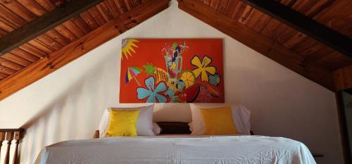 Appartements au cœur de Maharepa في Maharepa: غرفة نوم بسرير مع لوحة على الحائط