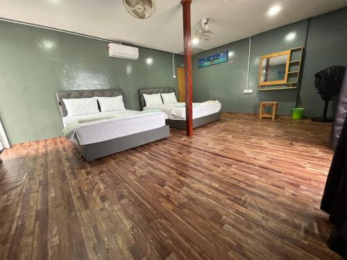 1 dormitorio con 2 camas y suelo de madera en Khafii House en Kampong Pasir Panjang