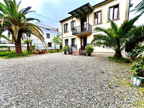 a house with palm trees and a gravel driveway at Дом с 5 спальнями в Батуми in Batumi