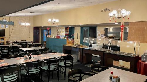 a restaurant with tables and chairs and a kitchen at Lively Inn and Suites - Sudbury in Naughton